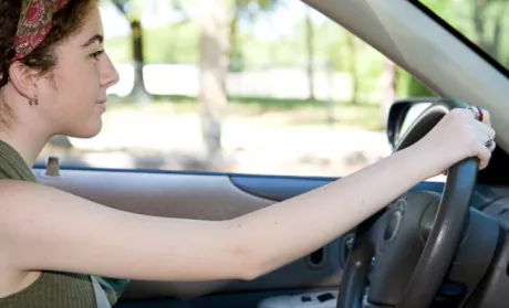 Driver looking ahead with one hand on steering wheel